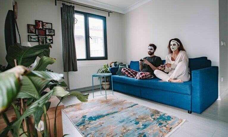 Para siedząca na kanapie w piżamach i maseczkach na twarzy