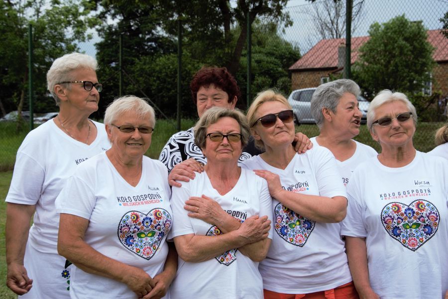 Zdjęcie przedstawia osiem kobiet ubranych w białe koszulki z napisem Koło Gospodyń Wiejskich w Niemcach, pod napisem na koszulkach jest kolorowe serce -logo koła. 