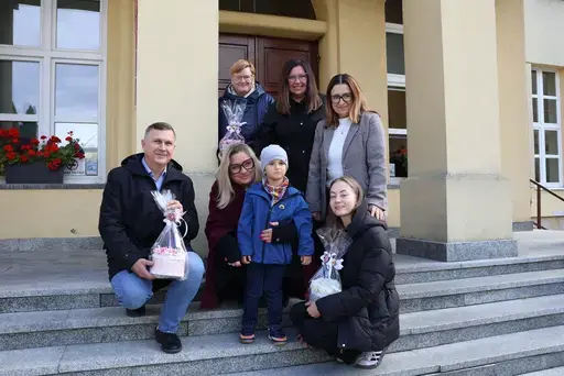 Przekazanie białego busa Renault Trafic z czerwoną kokardą przed budynkiem Starostwa Powiatowego w Lublinie: winda w tylnych drzwiach, wywiady dla telewizji, wspólne zdjęcia z podopiecznymi i spotkanie przy stole w sali.