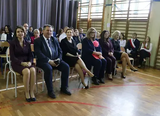 Obchody Powiatowego Dnia Edukacji Narodowej w sali gimnastycznej szkoły w Bełżycach: wystąpienia przy mównicy, wręczanie dyplomów i upominków nauczycielom oraz uczniom, goście na widowni, poczet sztandarowy i występ muzyczny uczniów.