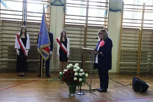 Obchody Powiatowego Dnia Edukacji Narodowej w sali gimnastycznej szkoły w Bełżycach: wystąpienia przy mównicy, wręczanie dyplomów i upominków nauczycielom oraz uczniom, goście na widowni, poczet sztandarowy i występ muzyczny uczniów.