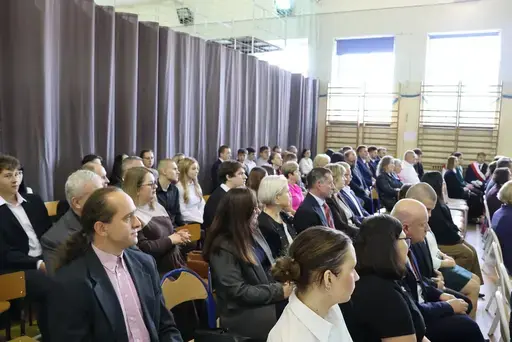 Obchody Powiatowego Dnia Edukacji Narodowej w sali gimnastycznej szkoły w Bełżycach: wystąpienia przy mównicy, wręczanie dyplomów i upominków nauczycielom oraz uczniom, goście na widowni, poczet sztandarowy i występ muzyczny uczniów.