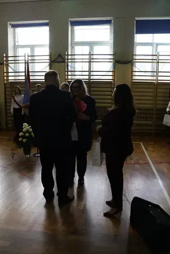 Obchody Powiatowego Dnia Edukacji Narodowej w sali gimnastycznej szkoły w Bełżycach: wystąpienia przy mównicy, wręczanie dyplomów i upominków nauczycielom oraz uczniom, goście na widowni, poczet sztandarowy i występ muzyczny uczniów.