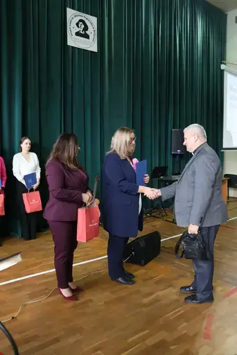 Obchody Powiatowego Dnia Edukacji Narodowej w sali gimnastycznej szkoły w Bełżycach: wystąpienia przy mównicy, wręczanie dyplomów i upominków nauczycielom oraz uczniom, goście na widowni, poczet sztandarowy i występ muzyczny uczniów.