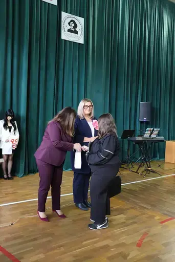 Obchody Powiatowego Dnia Edukacji Narodowej w sali gimnastycznej szkoły w Bełżycach: wystąpienia przy mównicy, wręczanie dyplomów i upominków nauczycielom oraz uczniom, goście na widowni, poczet sztandarowy i występ muzyczny uczniów.