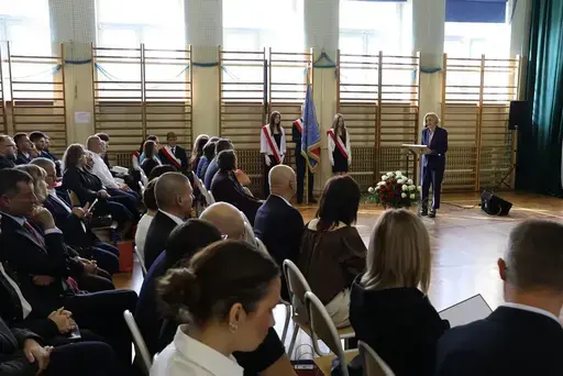 Obchody Powiatowego Dnia Edukacji Narodowej w sali gimnastycznej szkoły w Bełżycach: wystąpienia przy mównicy, wręczanie dyplomów i upominków nauczycielom oraz uczniom, goście na widowni, poczet sztandarowy i występ muzyczny uczniów.