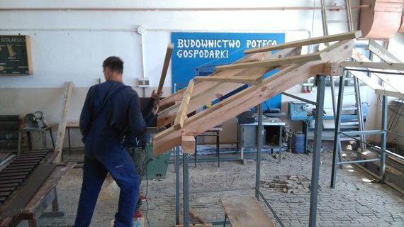 
                                                    2 osoby tworzące konstrukcję z drewna
                                                