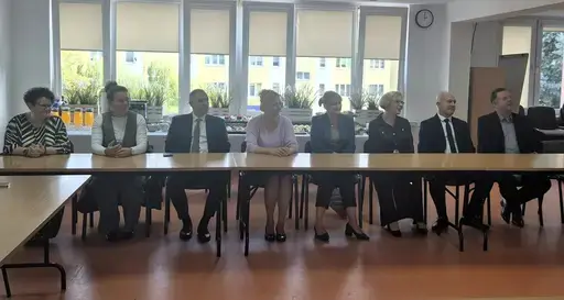 
                                                    Uroczystość w Starostwie Powiatowym w Rykach. Nagrodzeni nauczyciele i pracownicy oświaty z kwiatami i dyplomami pozują z władzami powiatu na tle granatowej ścianki z napisem Powiat Rycki.
                                                