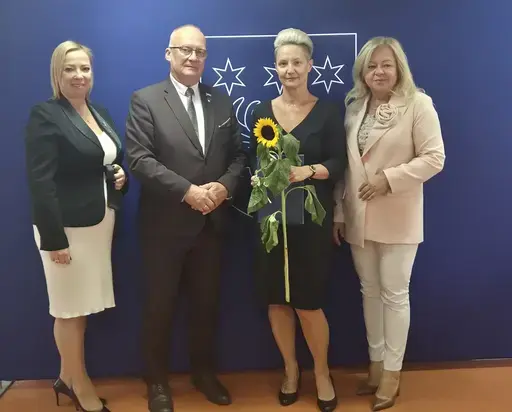 
                                                    Uroczystość w Starostwie Powiatowym w Rykach. Nagrodzeni nauczyciele i pracownicy oświaty z kwiatami i dyplomami pozują z władzami powiatu na tle granatowej ścianki z napisem Powiat Rycki.
                                                