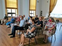 Zdjęcie przedstawia publiczność zgromadzoną na sali w Miejskim Domu Kultury, słuchającą prelekcji. N