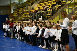 Uczniowie stojący w grupie podczas apelu w hali.