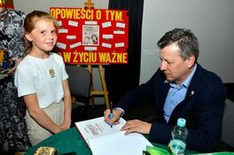 Marek Michalak podpisuje książkę uczennicy