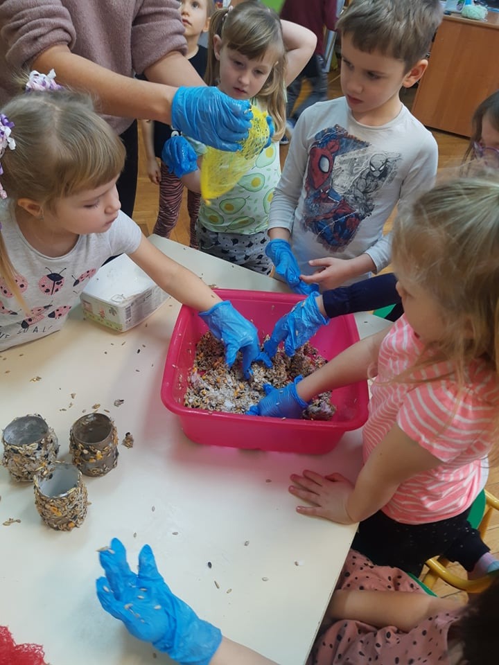 Przedszkolaki dokarmiają ptaki zimą