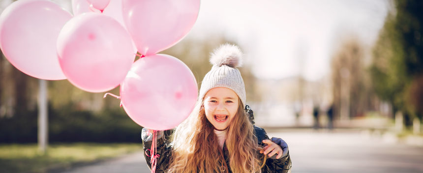Uśmiechnięta dziewczynka z balonami różowymi