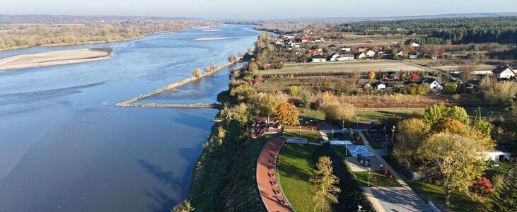 Widok z lotu ptaka na meandrującą rzekę z lewym brzegiem pokrytym drzewami, a prawym z zabudowaniami i promenadą.