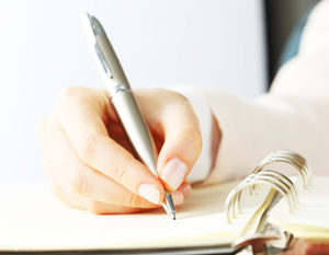 Ręka trzymająca długopis i pisząca po kartce