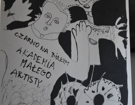 Czarno-biały plakat z abstrakcyjnymi rysunkami twarzy i kwiatów. Na dole napis: "Ziarno na białym. Akademia Małego Artysty". Plakat stoi na sztaludze.