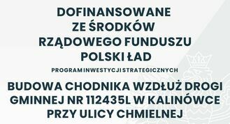 Tablica informacyjna mówiąca o dofinansowaniu z rządowego funduszu Polski Ład na budowę chodnika wzdłuż drogi gminnej numer 112435L w Kalinówce przy ulicy Chmielnej.