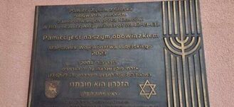 Tablica pamiątkowa z inskrypcją w językach polskim i hebrajskim oraz symbolami judaizmu, w tym Menorą i Gwiazdą Dawida.