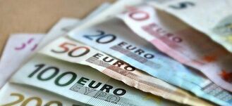 Kilka banknotów euro rozłożonych na stole, w tym nominały 5, 20, 50, 100, 200 i 500 euro. Banknoty są ułożone jeden na drugim, ukazując różnorodność kolorów i wzorów.