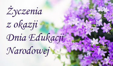Na zdjęciu napis Życzenia z okazji Dnia Edukacji Narodowej na tle kwiatów