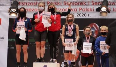 Na zdjęciu zawodniczki w podnoszeniu ciężarów na podium