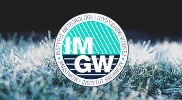 Logo IMGW na tle zmarzniętej trawy