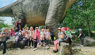 grupa dzieci przed makieta dinozaura