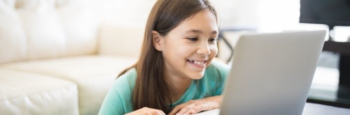 Uśmiechnięta dziewczynka przy laptopie
