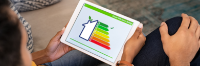 Osoba trzyma tablet wyświetlający grafikę z baterią i wskaźnikami poziomu naładowania z kolorowymi paskami od czerwonego do zielonego.