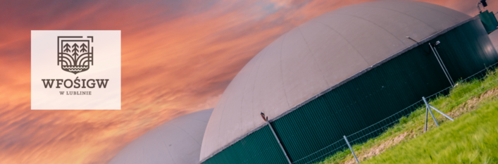 Duży, półowalny hangar z zielonym dachem na tle zachmurzonego nieba o zachodzie słońca z logo "WFOSiGW w Olsztynie" w lewym górnym rogu.