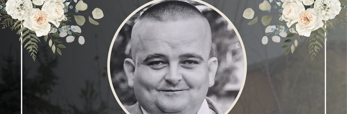 Na czarnym tle znajduje się zdjęcie mężczyzny w górnej części. Poniżej tekst kondolencyjny z informacją o jego śmierci. Wokół dekoracja z białych kwiatów i zielonych liści.