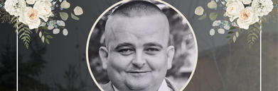 Na czarnym tle znajduje się zdjęcie mężczyzny w górnej części. Poniżej tekst kondolencyjny z informacją o jego śmierci. Wokół dekoracja z białych kwiatów i zielonych liści.