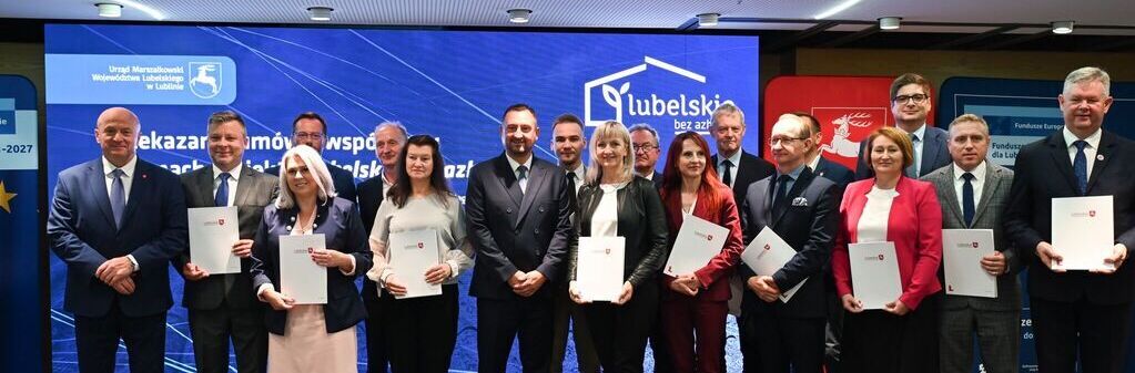 Grupa osób w formalnych strojach stoi na scenie z dyplomami w rękach. W tle widoczne są loga i napisy związane z regionem lubelskim.