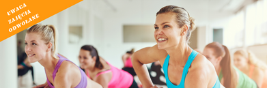 Grupa ludzi wykonuje ćwiczenia fitness w sali gimnastycznej. U góry na czerwono napis odwołujący zajęcia 17 i 18 marca z powodu gminy Wólka. Po prawej stronie ikona hantli na pomarańczowym tle.