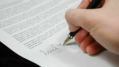 dłoń trzymająca pióro i podpisująca dokument