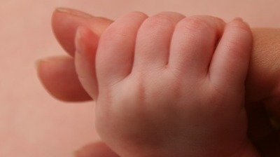 dłoń dziecka trzymająca za palec dłoni osoby dorosłej