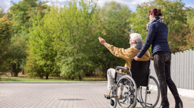 zdjęcie osoby poruszającej się na wózku inwalidzkiej i jej opiekuna
