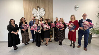 zdjęvie stojącej grupy ludzi, trzymającej bukiety kwiatów