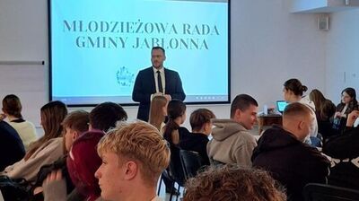 zdjęcie zastępcy wójta. który opowiada o działalności urzędu grupie uczniów