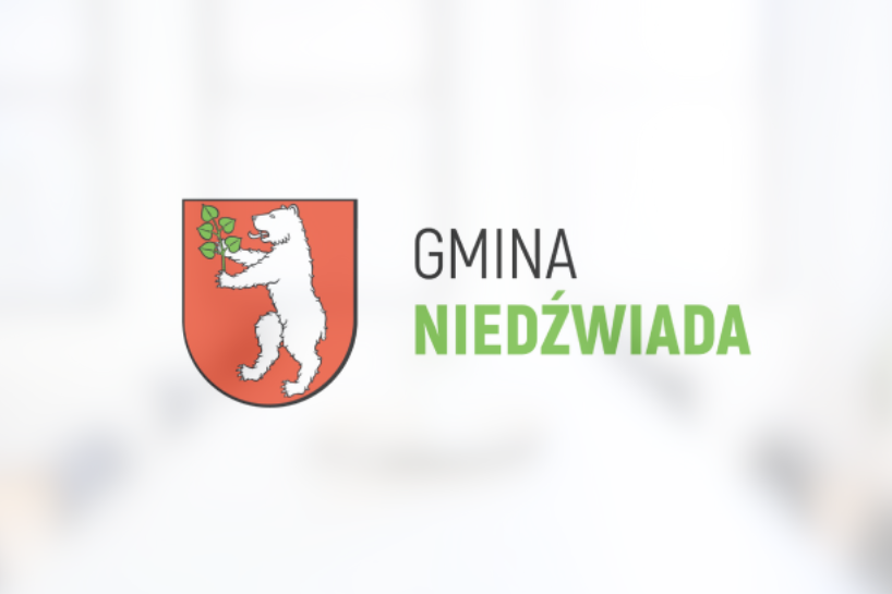 Logo gminy Niedźwiada z herbem przedstawiającym białego niedźwiedzia na czerwonym tle oraz napisem "GMINA NIEDŹWIADA" na szarym banerze.