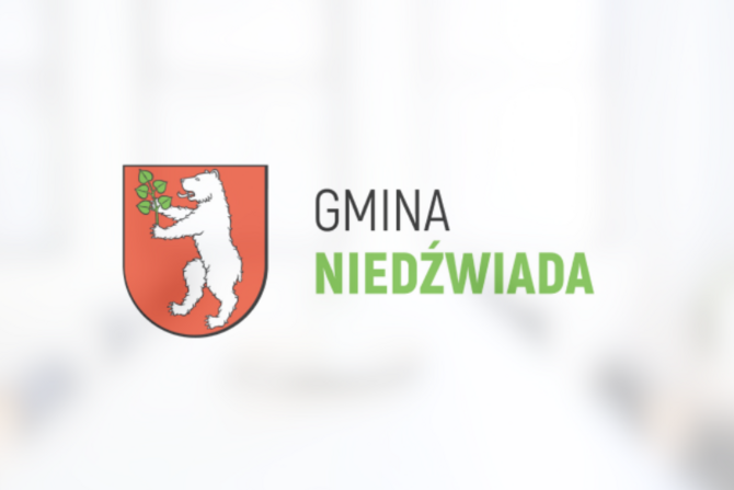 Herb Gminy Niedźwiada przedstawiający białego niedźwiedzia trzymającego zieloną gałązkę na czerwonym tle, powyżej napis "GMINA NIEDŹWIADA".