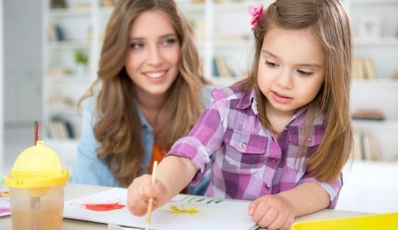 Matka z dzieckiem, dziewczynka maluje farbami po kartce papieru.
