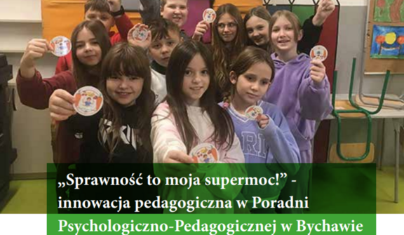 Grupa uśmiechniętych dzieci w klasie pokazuje okrągłe naklejki, tytuł na zdjęciu: "Sprawność to moja supermoc!" - innowacja pedagogiczna.