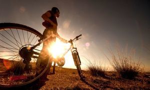 Rowerzysta z rowerem o zachodzie słońca
