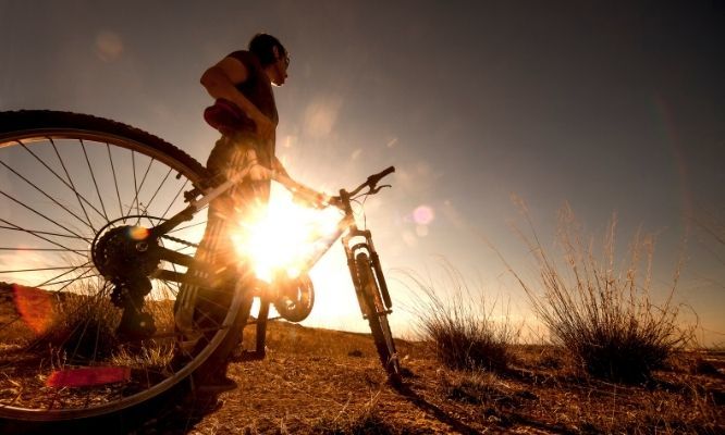 Rowerzysta z rowerem przy zachodzie słońca