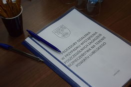 Zdjęcie przedstawia dokument leżący na biurku oraz długopisy