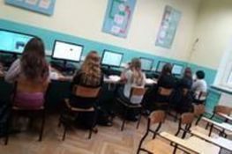 Zdjęcie przedstawia uczniów siedzących w klasie przy komputerach 