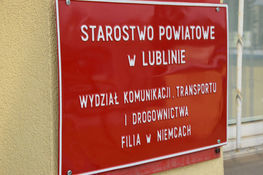 Tabliczka czerwona z napisami Starostwo Powiatowe w Lublinie Wydział Komunikacji, Transportu i Drogownictw