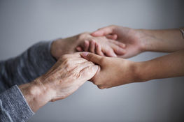 zbliżenie dwóch osób trzymających się za ręce w geście wsparcia i pomocy